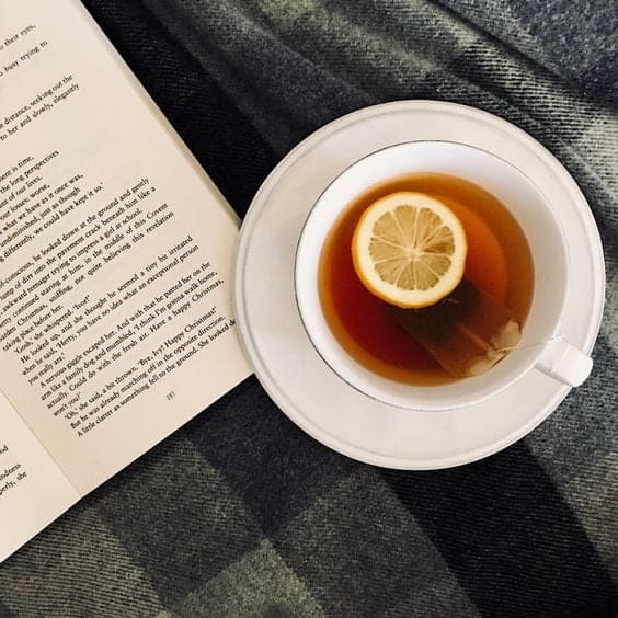 Open book and mug of honey and lemon tea.